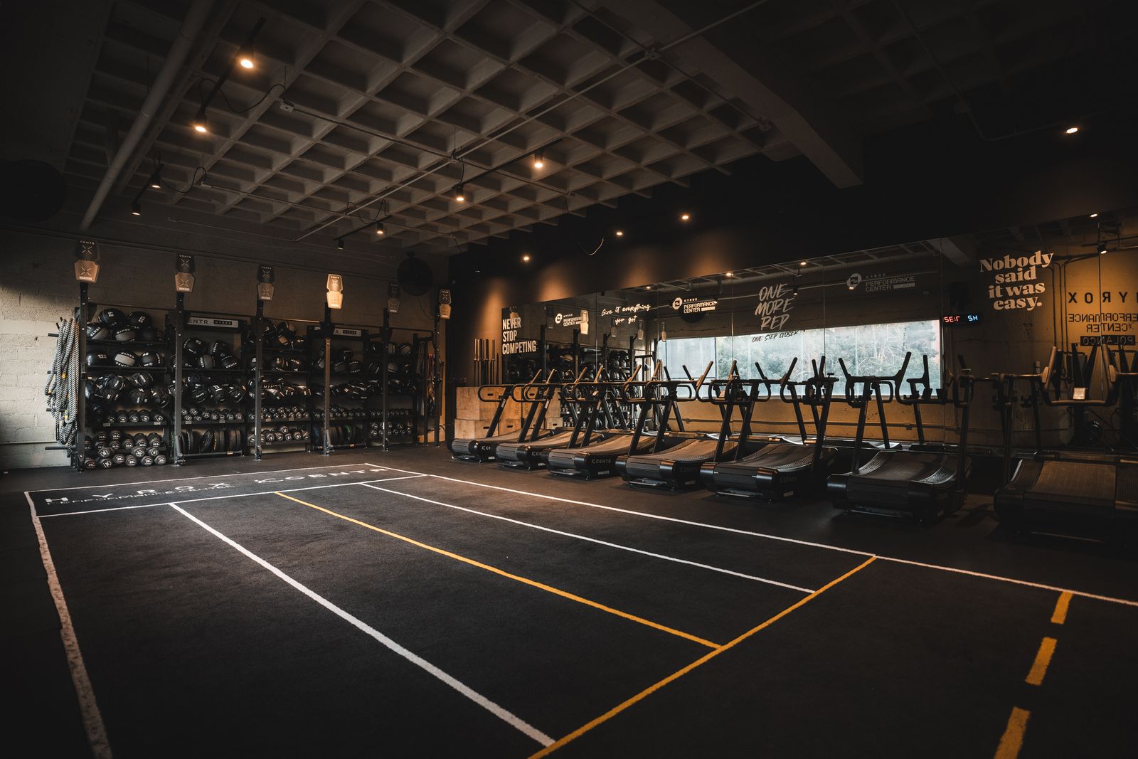 Piso de entrenamiento del HYROX Performance Center con carriles y racks CENTR x HYROX